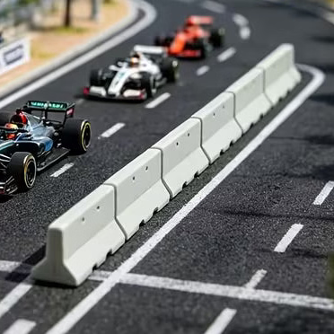 A miniature model racetrack scene with several Formula 1 cars racing on a curved asphalt track, alongside grandstands filled with tiny spectators and trees under a blue sky.