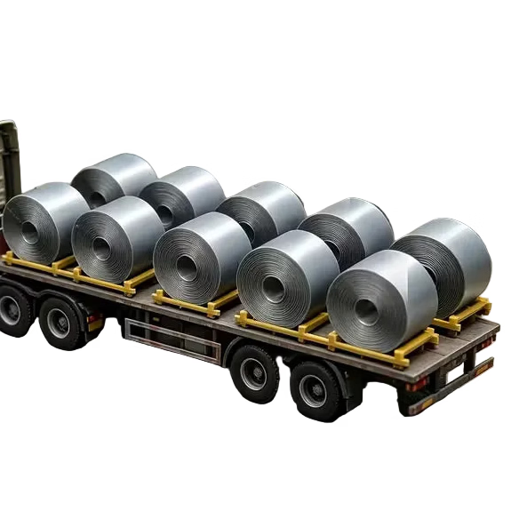 A miniature model flatbed truck carrying several large silver metal rolls, positioned in front of a small gray warehouse building on a gray concrete surface.